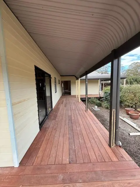 Finished hardwood verandah running the length of a weatherboard house under a curved verandah roof