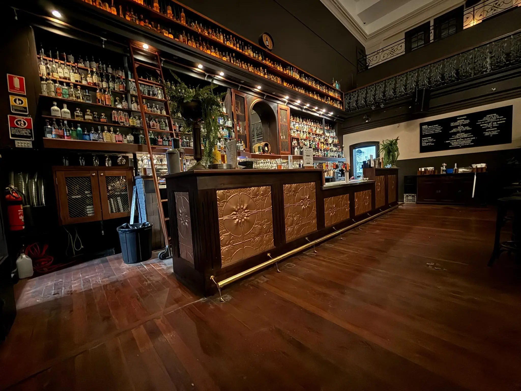 Heritage pub main bar with pressed metal bar front, tall spirits shelving and polished timber floor