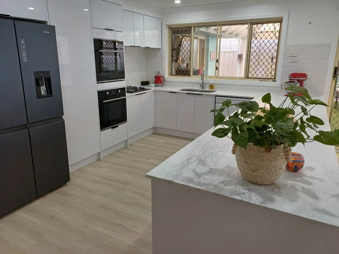 Renovated Newcastle kitchen with gloss white cabinetry, a wall oven tower, gas cooktop and a peninsula bench