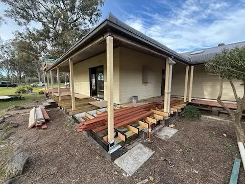 Verandah deck subframe with bearers and joists laid on new footings, decking boards stacked on site ready to fix