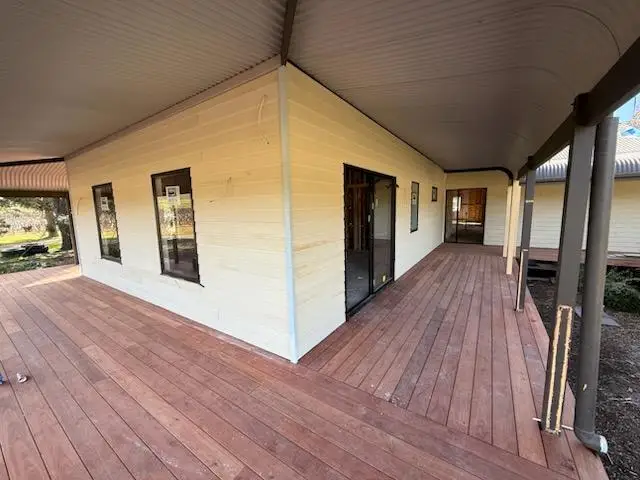 Completed hardwood wraparound verandah deck with painted posts and sliding doors opening onto the house